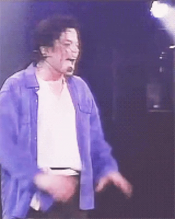 A Man Wearing A Blue Shirt And A White Shirt Is Singing Into A Microphone GIF