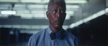A Man Wearing A Blue Shirt And Bow Tie Is Looking At The Camera . GIF