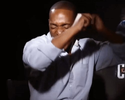 A Man Wearing A Blue Shirt Is Covering His Face With His Hand GIF