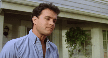 A Man Wearing A Blue Shirt Is Standing In Front Of A House GIF