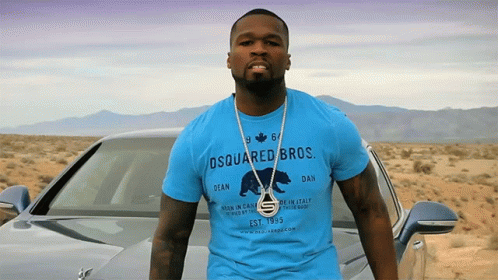 A Man Wearing A Blue Shirt That Says Dsquared Bros Stands In Front Of A Car GIF