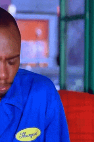A Man Wearing A Blue Shirt With A Yellow Badge That Says Heavygod On It GIF