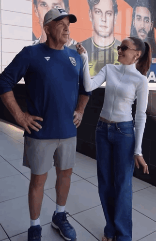 A Man Wearing A Blue Shirt With The Letter F On It Stands Next To A Woman GIF