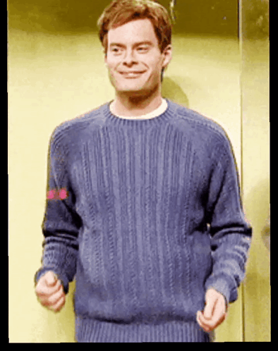 A Man Wearing A Blue Sweater Is Smiling And Making A Funny Face GIF