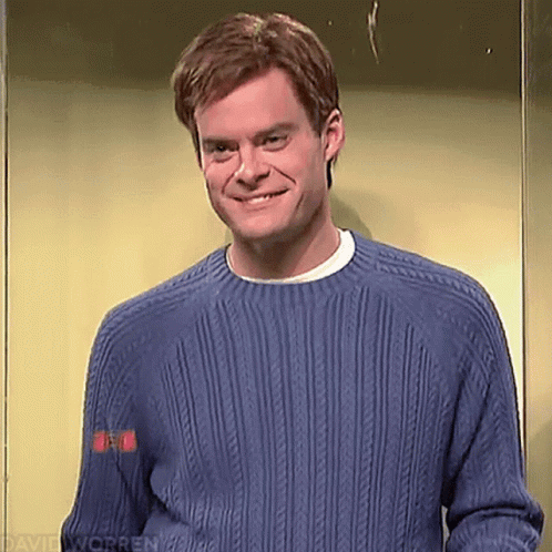 A Man Wearing A Blue Sweater Is Smiling While Standing In An Elevator . GIF
