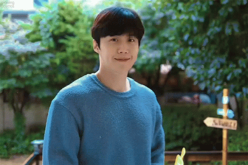 A Man Wearing A Blue Sweater Is Standing In Front Of A Sign That Says ' Shack ' On It . GIF
