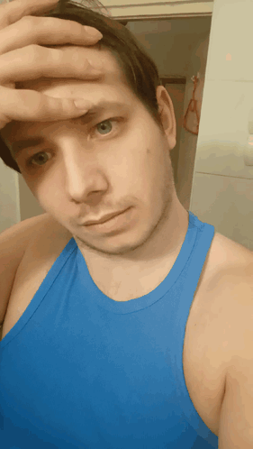 A Man Wearing A Blue Tank Top Wipes His Forehead With His Hand GIF