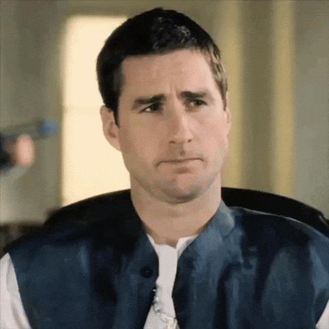 A Man Wearing A Blue Vest And A White Shirt Makes A Sad Face GIF