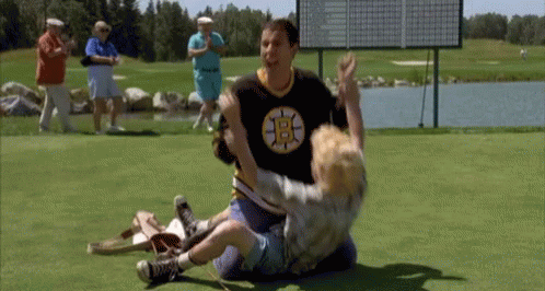 A Man Wearing A Boston Bruins Shirt Is Wrestling A Young Boy On A Golf Course . GIF
