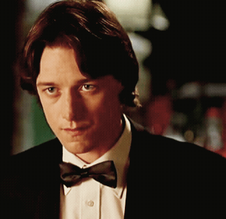 A Man Wearing A Bow Tie And A Suit Looks At The Camera GIF