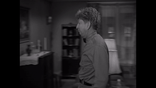A Man Wearing A Bow Tie Is Standing In A Doorway GIF