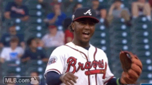 A Man Wearing A Braves Jersey Is Holding A Glove GIF