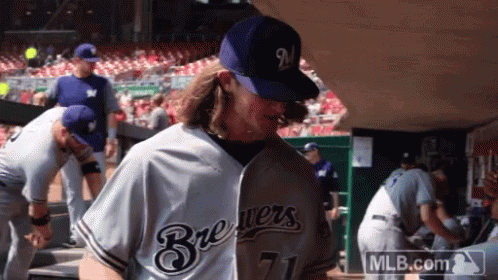 a man wearing a brewers jersey and a mlb.com logo