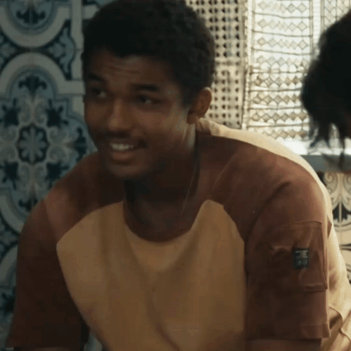 A Man Wearing A Brown And White Shirt With A Pocket On The Sleeve That Says ' R.i.p. ' GIF