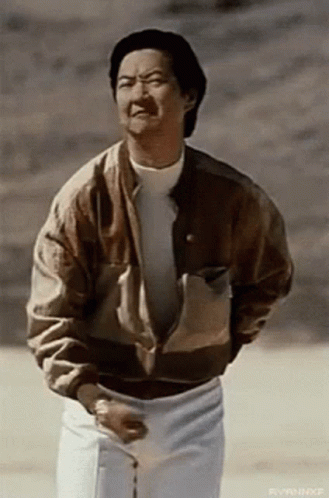 A Man Wearing A Brown Jacket And White Pants Is Standing In The Desert . GIF