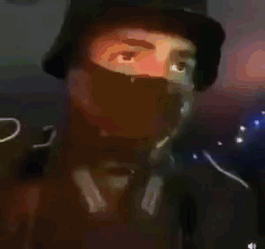 A Man Wearing A Bucket Hat And A Green Mask . GIF
