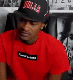 A Man Wearing A Bulls Hat And A Red T-Shirt Is Sitting In A Chair . GIF