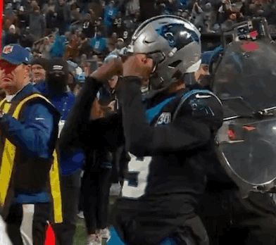 A Man Wearing A Carolina Panthers Helmet Stands In Front Of A Crowd . GIF