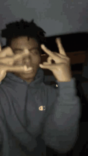 A Man Wearing A Champion Hoodie Is Making A Peace Sign With His Hands GIF