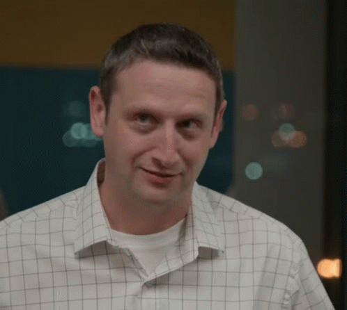 A Man Wearing A Checkered Shirt Looks At The Camera GIF