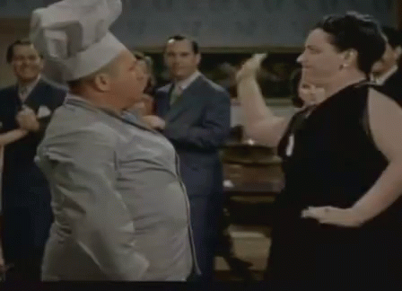 A Man Wearing A Chef 'S Hat Is Dancing With A Woman . GIF