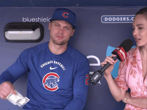 A Man Wearing A Chicago Cubs Shirt Is Being Interviewed By A Woman With A Microphone GIF