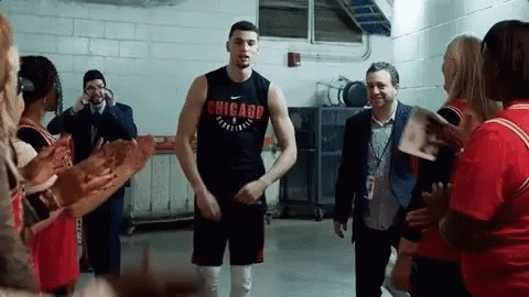 A Man Wearing A Chicago Shirt Stands In A Locker Room Surrounded By People GIF