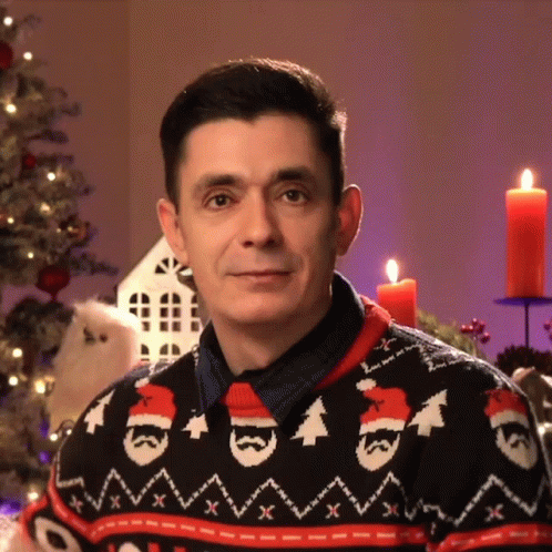 A Man Wearing A Christmas Sweater Has A Santa Hat On GIF
