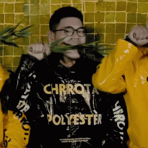 A Man Wearing A Chrrot Polyester Jacket Holds A Plant In His Mouth GIF