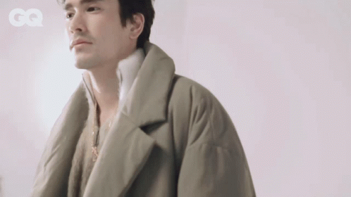 A Man Wearing A Coat With A Gq Logo On The Bottom GIF