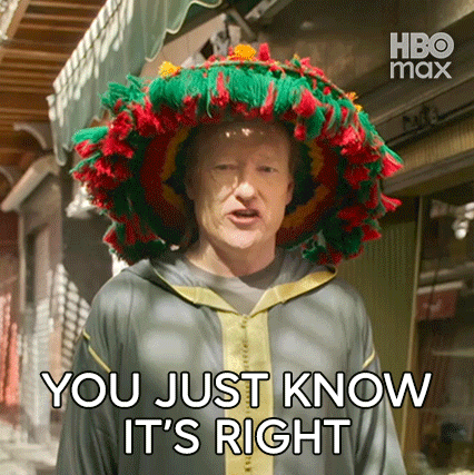 a man wearing a colorful hat is standing in front of a building and says `` you just know it 's right '' .
