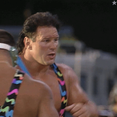 A Man Wearing A Colorful Swimsuit With The Letter S On It Is Talking To Another Man GIF