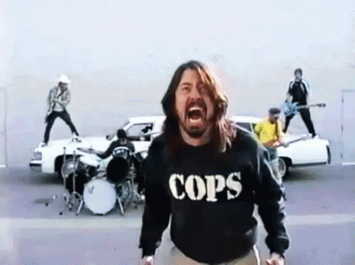 A Man Wearing A Cops Sweatshirt Is Screaming In Front Of A Band GIF