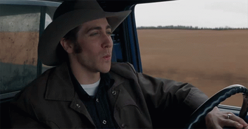 A Man Wearing A Cowboy Hat And A Leather Jacket Is Driving A Car GIF