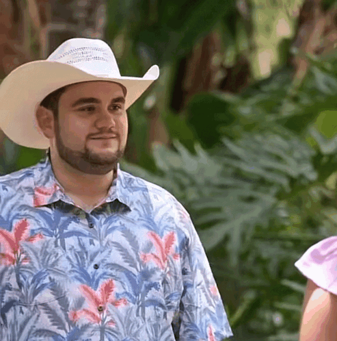 A Man Wearing A Cowboy Hat And A Shirt With Flowers On It GIF