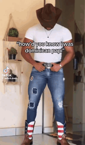 A Man Wearing A Cowboy Hat And Cowboy Boots Is Standing In Front Of A Wall . GIF