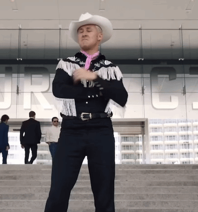 A Man Wearing A Cowboy Hat And Fringed Jacket Stands In Front Of A Building That Says Jrc GIF