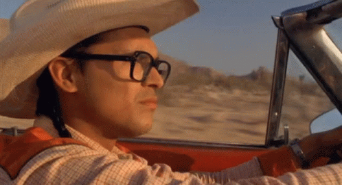 A Man Wearing A Cowboy Hat And Glasses Driving A Car GIF