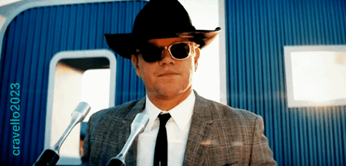A Man Wearing A Cowboy Hat And Sunglasses Stands In Front Of Microphones With The Year 2023 On The Bottom Right GIF