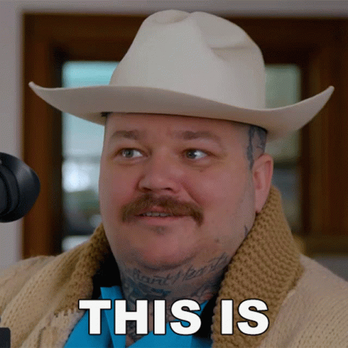 A Man Wearing A Cowboy Hat And Sweater Says " This Is " In Black Letters GIF