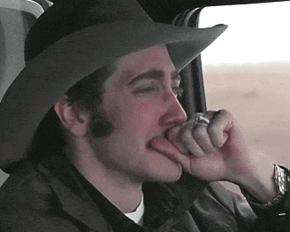 A Man Wearing A Cowboy Hat Is Biting His Finger GIF