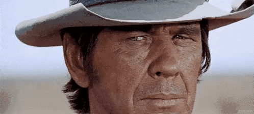 a man wearing a cowboy hat is making a funny face .