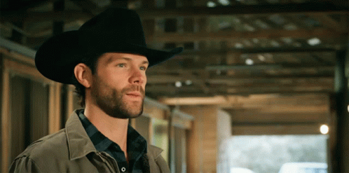 A Man Wearing A Cowboy Hat Is Standing In A Building GIF