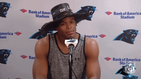 A Man Wearing A Cowboy Hat Stands In Front Of A Bank Of America Banner GIF