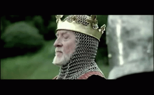 A Man Wearing A Crown And Chain Mail Is Standing In A Field GIF