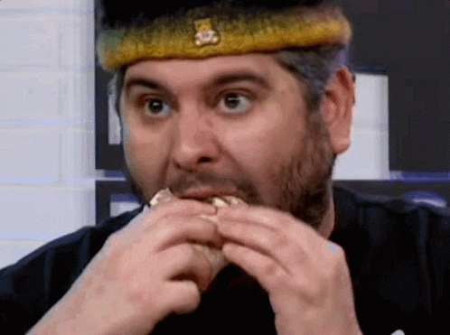 A Man Wearing A Crown Is Eating A Hamburger . GIF
