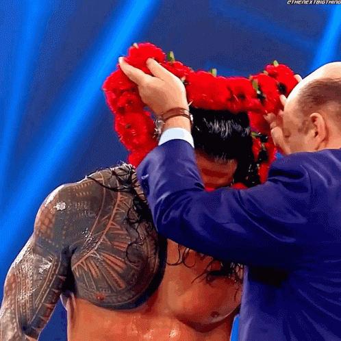 A Man Wearing A Crown Of Red Flowers On His Head GIF