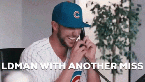A Man Wearing A Cubs Hat Is Talking On A Phone While Smiling . GIF