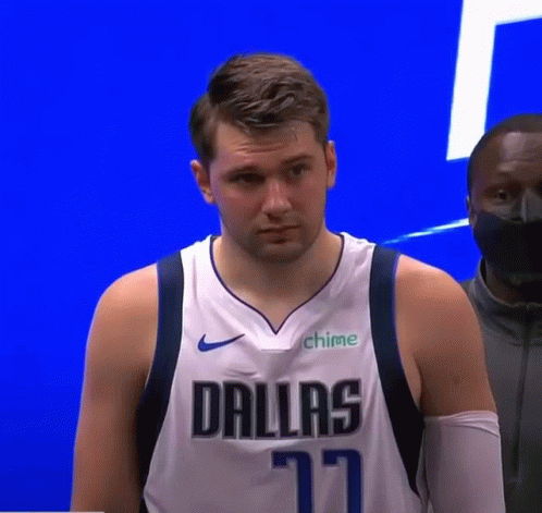 A Man Wearing A Dallas Jersey Is Standing In Front Of A Blue Wall . GIF