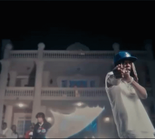 A Man Wearing A Dodgers Hat Is Standing In Front Of A House . GIF